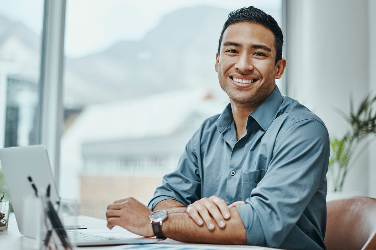Man smiling at an office desk after All-on-4 dental implants in Van Nuys, CA